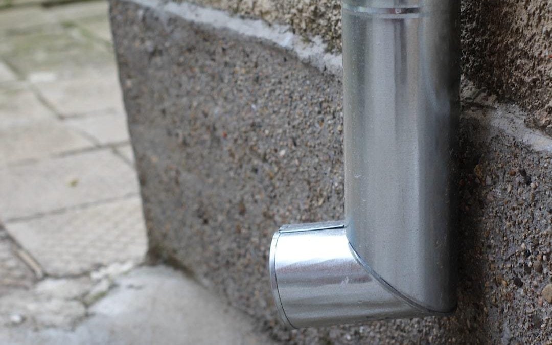 Metal downspout attached to a concrete wall.