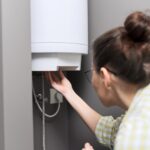 A woman adjusting settings on a wall-mounted boiler during essential maintenance.
