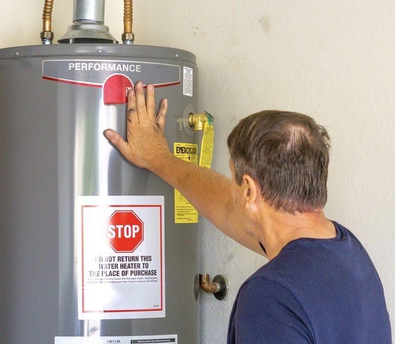 Man adjusting settings on a hot water heater in a residential setting.