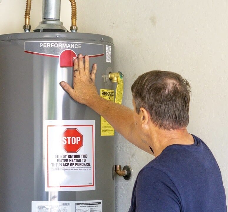 Man adjusting settings on a hot water heater in a residential setting.